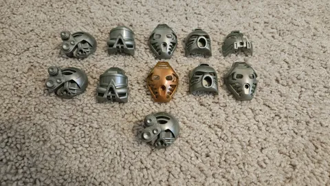 Lot Of 11 Lego Bionicle Kanohi Masks - 10 Silver And 1 Gold