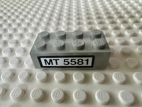 LEGO Brick 2 x 4 with Black 'MT 5581' on White Background 3001pb040