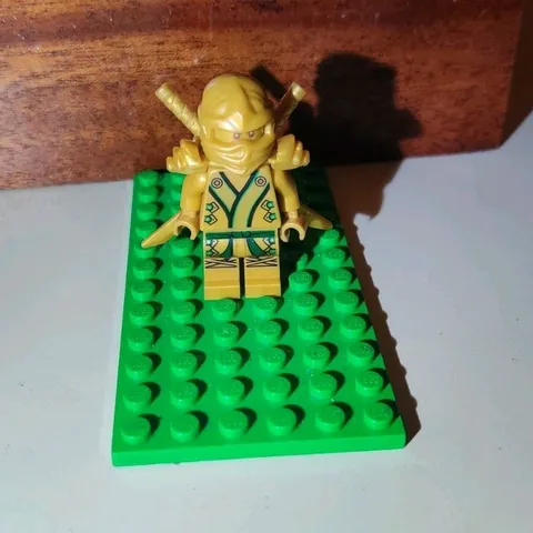 LEGO Gold Ninja Minifigure with Swords/Accessories on Green Baseplate