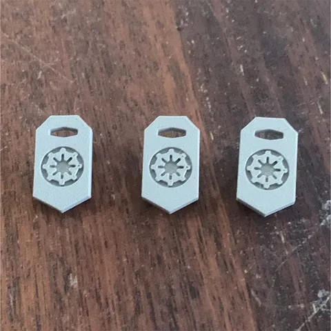 Three 3D printed grey imperial Lego shields.